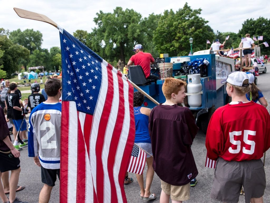 Henry Wieffering, 15, of St. Paul, Minn., carries a hockey stick with an American flag as part of the Langford Park Hockey float — which included its Zamboni. Tom Baker for MPR News 
