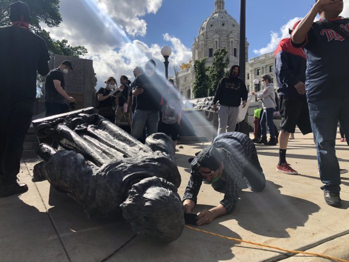 A protestor takes a photo of the fallen Christopher Columbus statue outside the Minnesota Capitol. (Twitter/Max Nesterak)