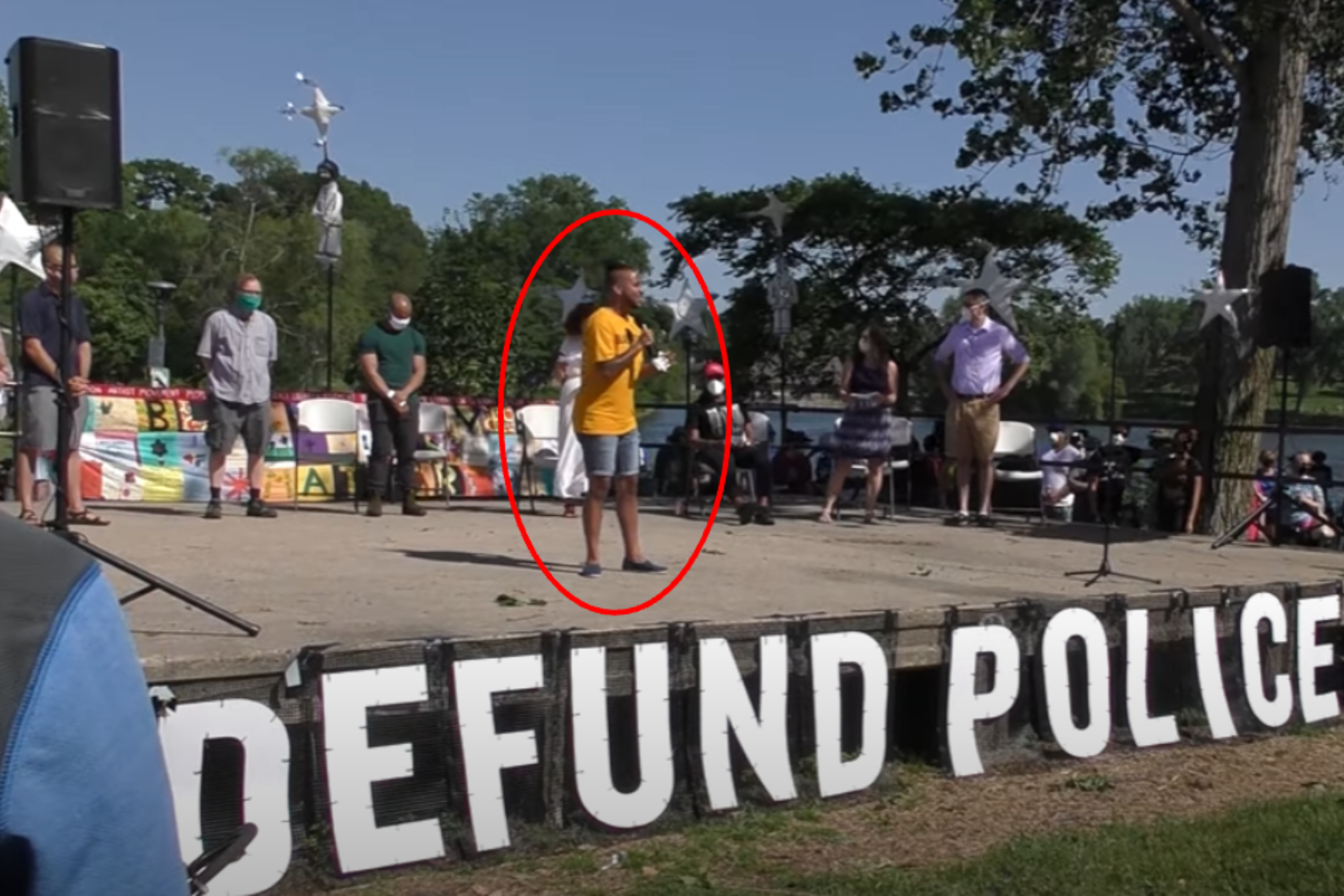 Phillipe Cunningham appears on a stage that says "DEFUND POLICE" last summer. (YouTube/UnicornRiot)