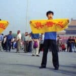A Chinese policeman (right) approaches Falun Gong practitioners in Tiananmen Square as they hold a banner that reads "Truthfulness Compassion Forbearance."