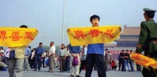 A Chinese policeman (right) approaches Falun Gong practitioners in Tiananmen Square as they hold a banner that reads "Truthfulness Compassion Forbearance."