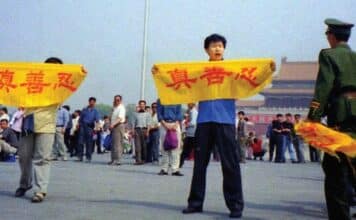 A Chinese policeman (right) approaches Falun Gong practitioners in Tiananmen Square as they hold a banner that reads "Truthfulness Compassion Forbearance."