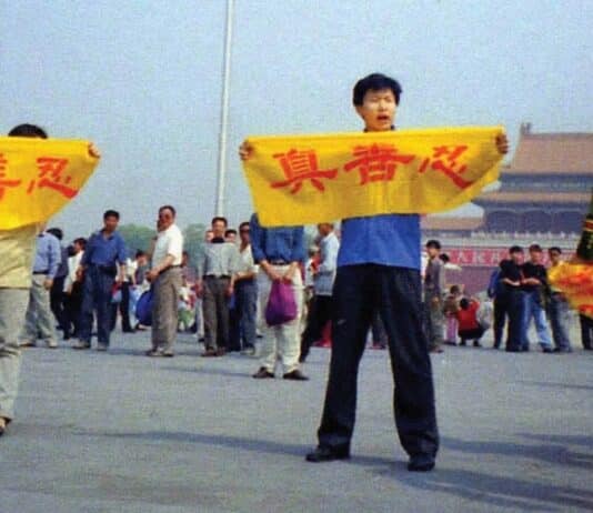 A Chinese policeman (right) approaches Falun Gong practitioners in Tiananmen Square as they hold a banner that reads "Truthfulness Compassion Forbearance."