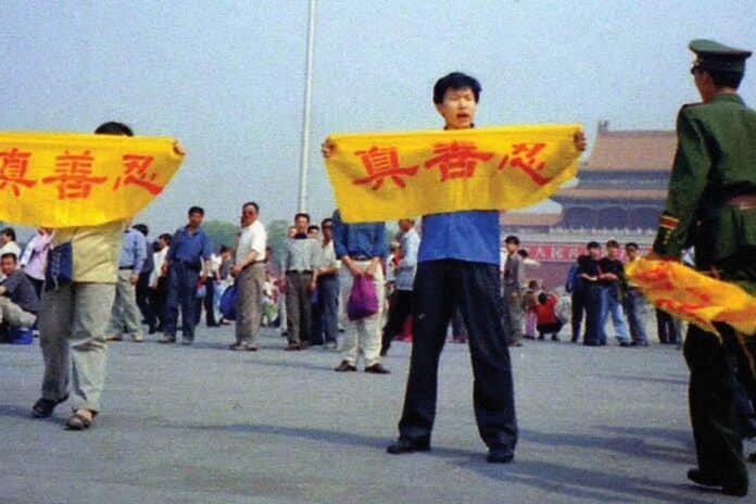 A Chinese policeman (right) approaches Falun Gong practitioners in Tiananmen Square as they hold a banner that reads "Truthfulness Compassion Forbearance."