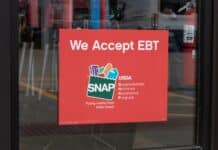 A SNAP and EBT accepted here sign displayed in a store window.