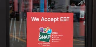 A SNAP and EBT accepted here sign displayed in a store window.