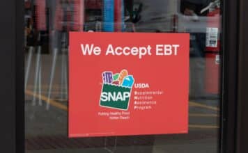 A SNAP and EBT accepted here sign displayed in a store window.