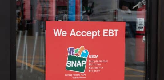 A SNAP and EBT accepted here sign displayed in a store window.
