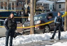 Minneapolis police officers stand by the scene where Renee Good was killed in January 2026.