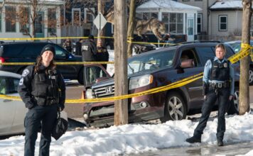Minneapolis police officers stand by the scene where Renee Good was killed in January 2026.