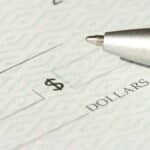 A close-up view of a blank check with a pen positioned near the dollar box.