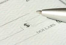 A close-up view of a blank check with a pen positioned near the dollar box.