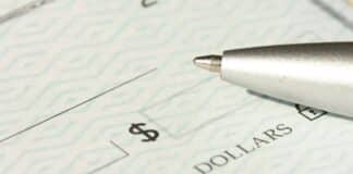 A close-up view of a blank check with a pen positioned near the dollar box.