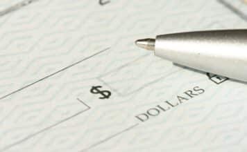 A close-up view of a blank check with a pen positioned near the dollar box.