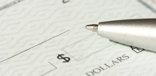 A close-up view of a blank check with a pen positioned near the dollar box.