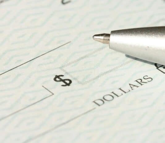 A close-up view of a blank check with a pen positioned near the dollar box.