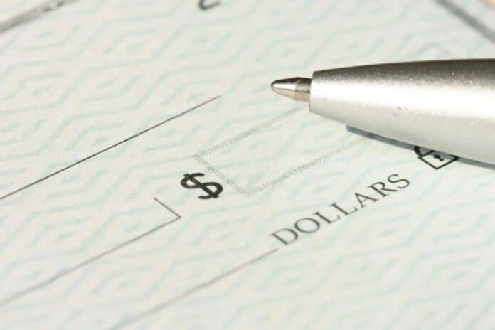 A close-up view of a blank check with a pen positioned near the dollar box.