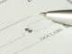 A close-up view of a blank check with a pen positioned near the dollar box.